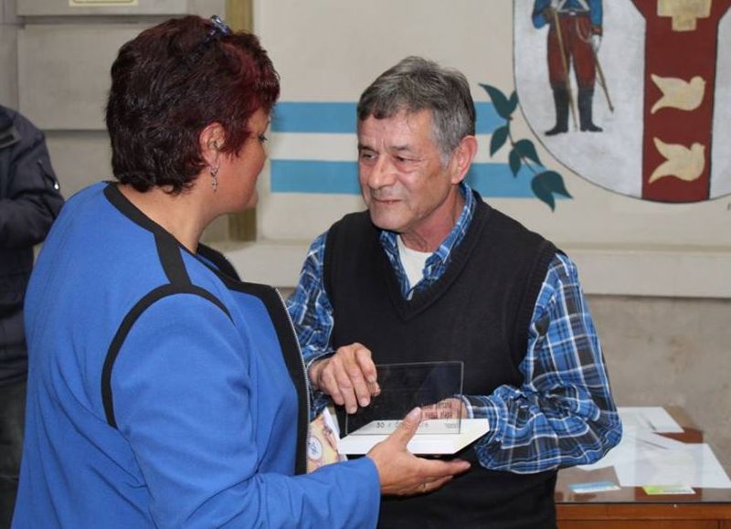 Una plaqueta y medalla le entregan en reconocimiento a su labor.